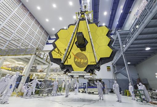 Los técnicos de la NASA levantan el telescopio, usando una grúa, y lo mueven dentro de una sala limpia en el Centro de Vuelo Espacial Goddard de la NASA en Greenbelt, Maryland (EE.UU.)