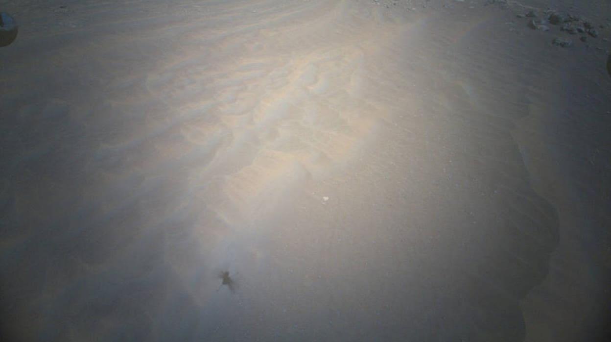 Imagen de la cámara de navegación capturada justo cuando el Ingenuity despegaba para el Vuelo 19, que muestra la arena acumulada saliendo volando de una de sus patas