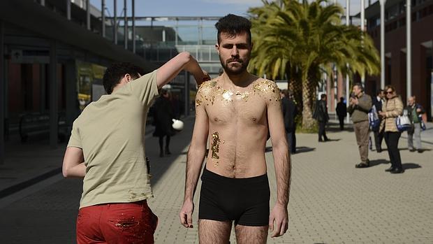 El artista Iván Sikic pega láminas doradas en el cuerpo de un refugiado sirio. Forma parte de una performance