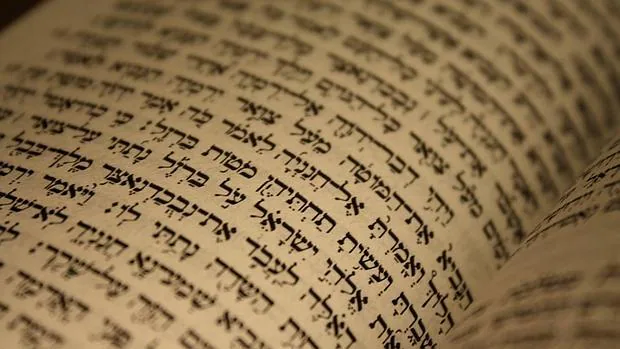 Arriba, detalle de una página sacada de una Biblia hebrea cuya estructura es tripartita y está marcada por la voz de Dios: Ley, los Profetas y los Escritos