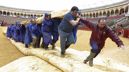 Los operarios retiran la lona del ruedo