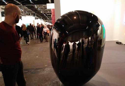 Un visitante se refleja en una escultura