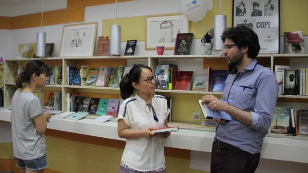 Guillermo Bravo atiende a dos clientas en la librería Mil Gotas, el Instituto Cervantes de Pekín