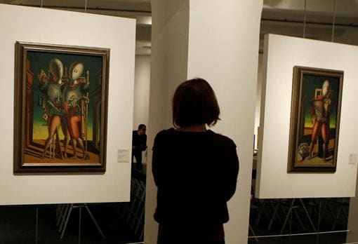 Una mujer observa dos obras de Giorgio de Chirico en la exposición