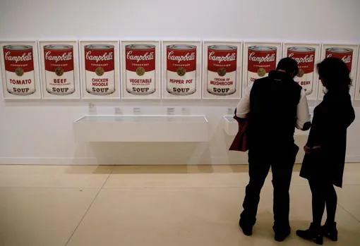 Dos personas ante la obra «Campbell Soup» (1968), de Andy Warhol, en la exposición