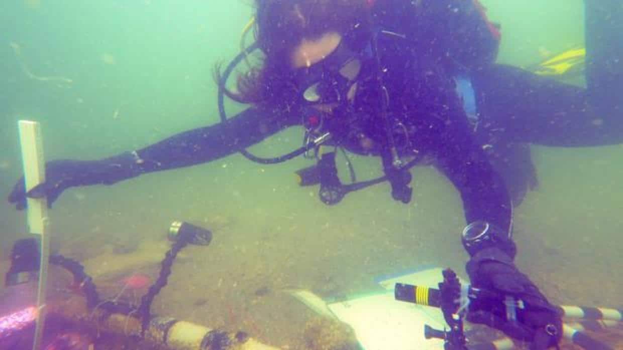 La socia de Florida Public Archaeology Network, Nicole Grinnan, mide la profundidad de la unidad de prueba con un nivel láser y una regla plegable en el sitio arqueológico llamado Manasota Key Offshore
