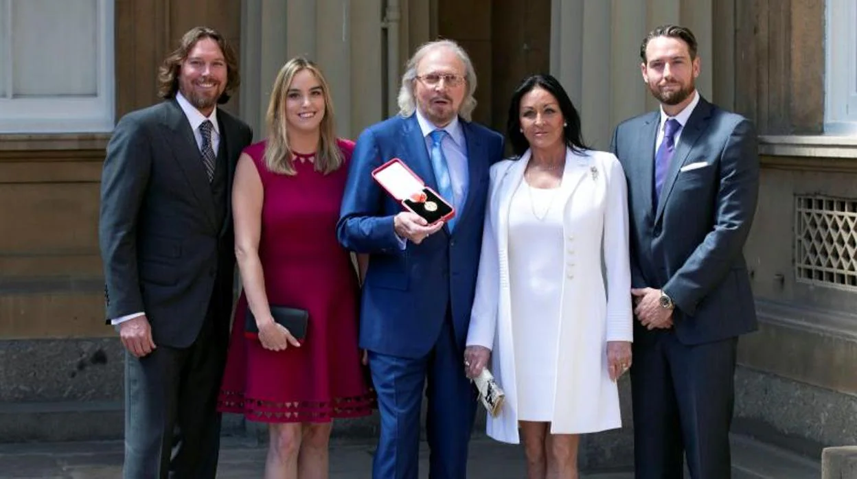 Barry Gibb (en el centro) posa con su familia mientras sostiene su condecoración