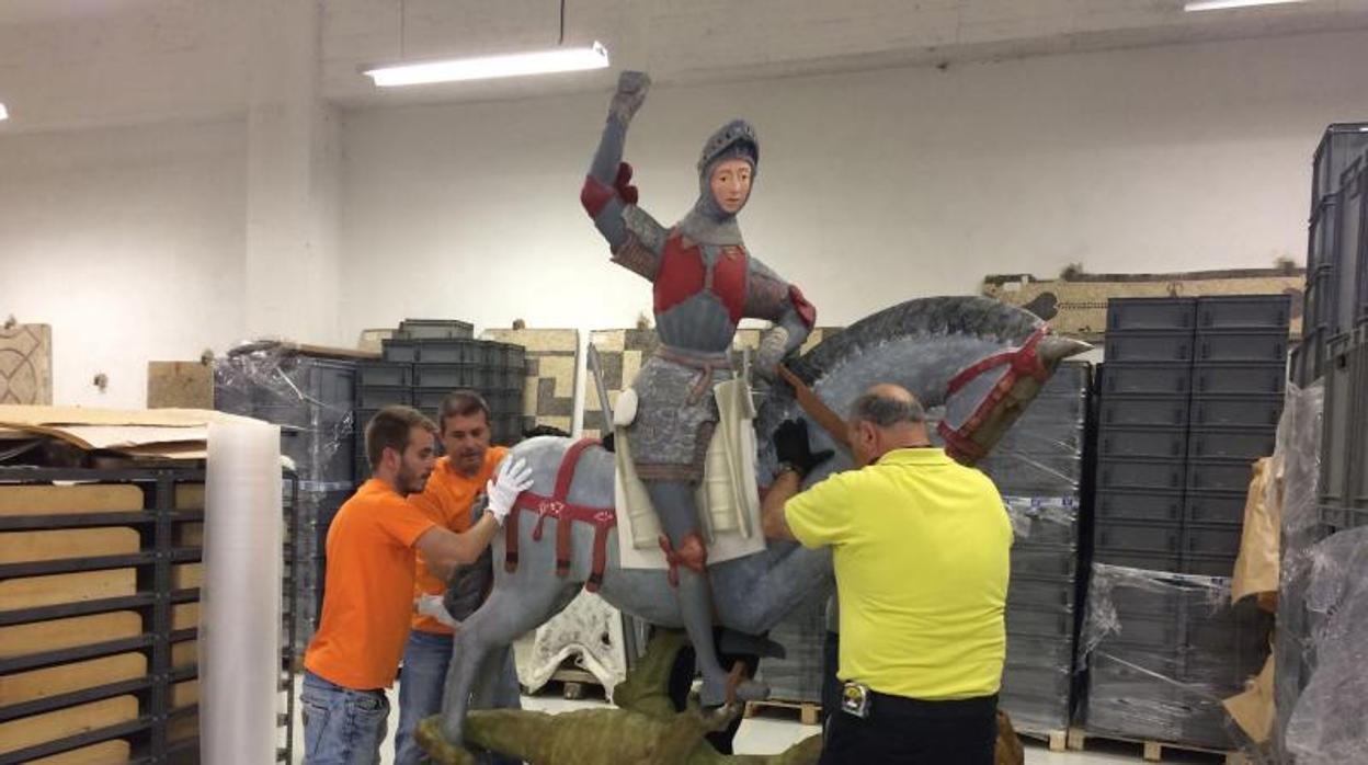 un grupo de operarios traslada la talla policromada de San Jorge a los almacenes de Patrimonio Histórico de Arqueología