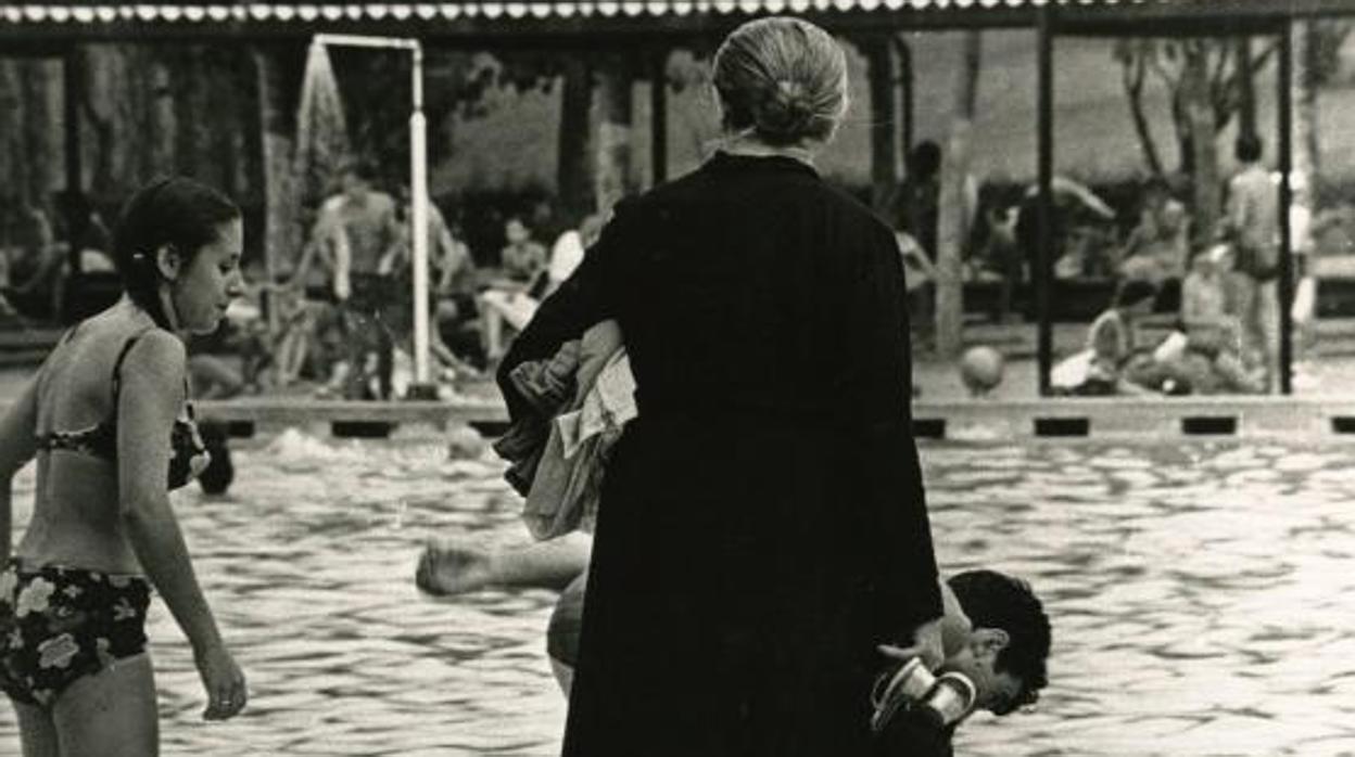 Una mujer vestida de negro en una piscina pública en el año 1968