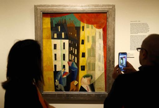 Dos personas observan la obra «Arquitectura II (El hombre de Potin)», 1921, de Lyonel Feininger