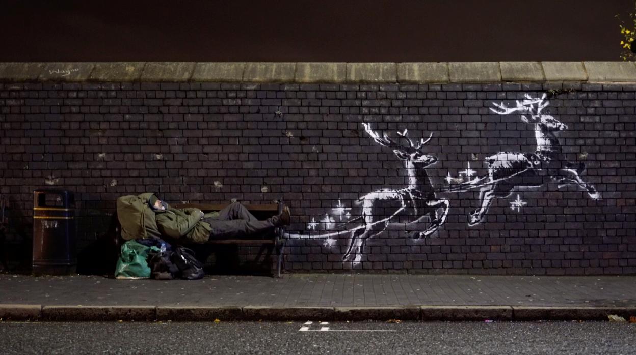 El mural de Banksy, en el que dos renos parecen tirar del banco en el que está acostado un sintecho