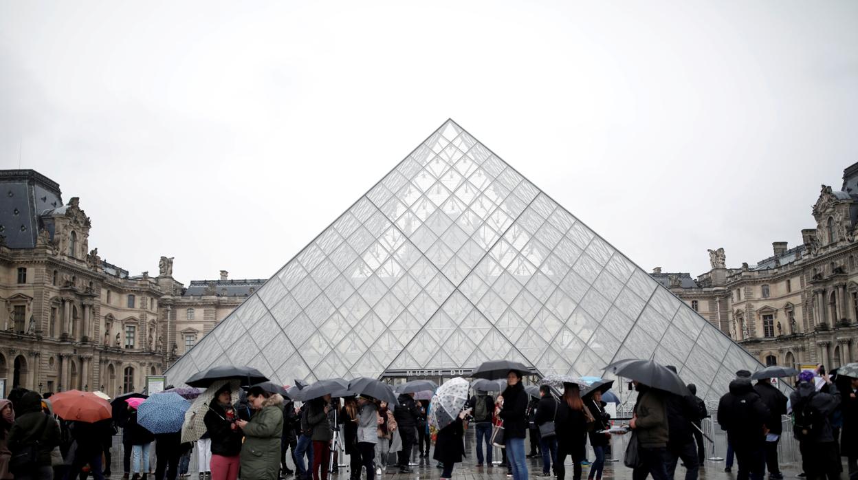 Los turistas hacen cola frente al Louvre