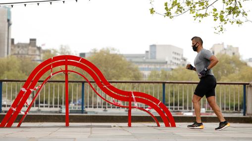 Un hombre con mascarilla corre por South Bank, en Londres