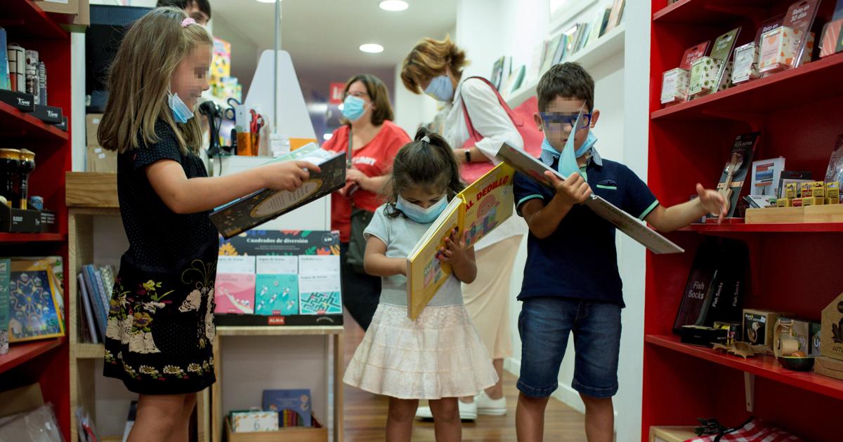 Un grupo de niños ataviados con mascarillas, en una librería de Orense