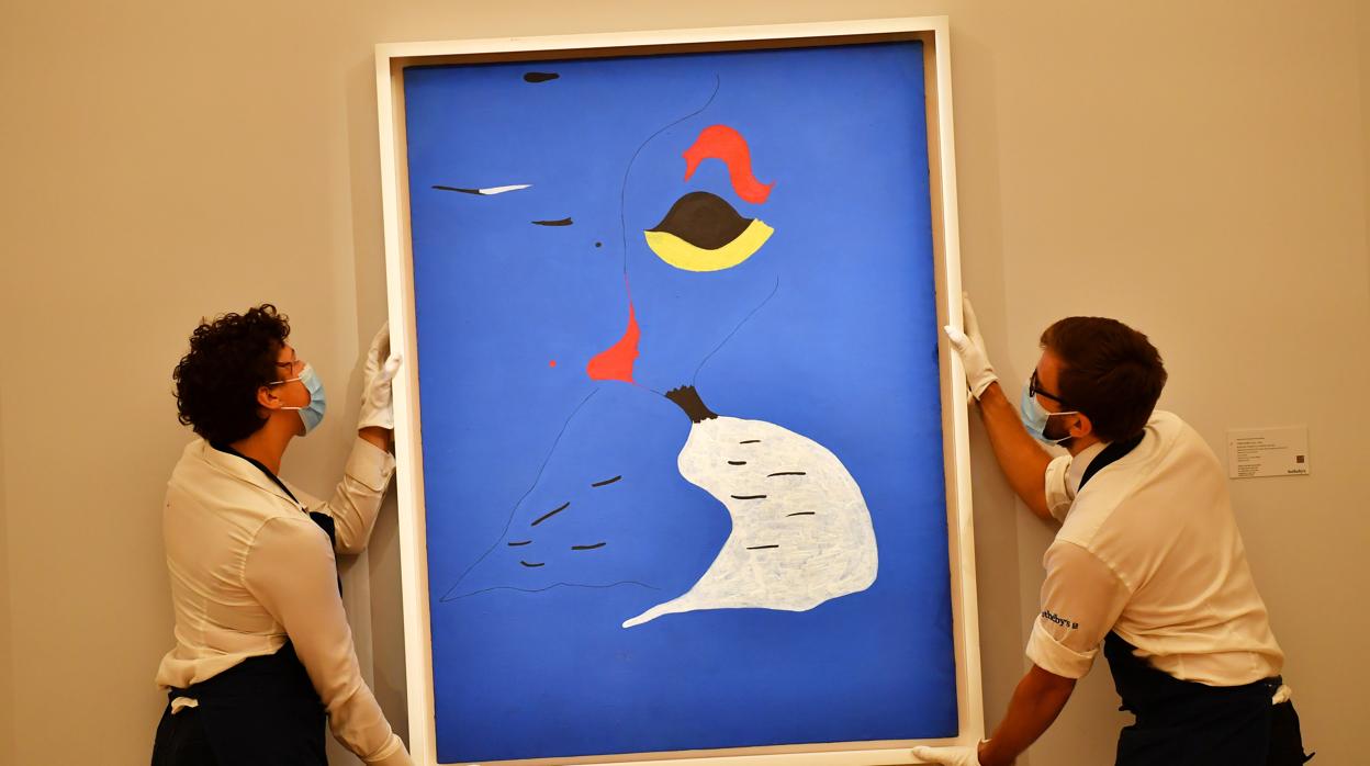 Dos empleados de Sotheby's, con «Peinture (femme au chapeau rouge)», de Miró