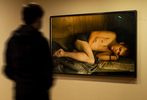 Un hombre admira «"Doc" Kelso durmiendo» (2008), de Tim Hetherington