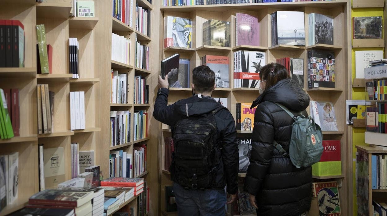 Dos clientes, con sus respectivas mascarillas, ojean libros en una librería del centro de Madrid