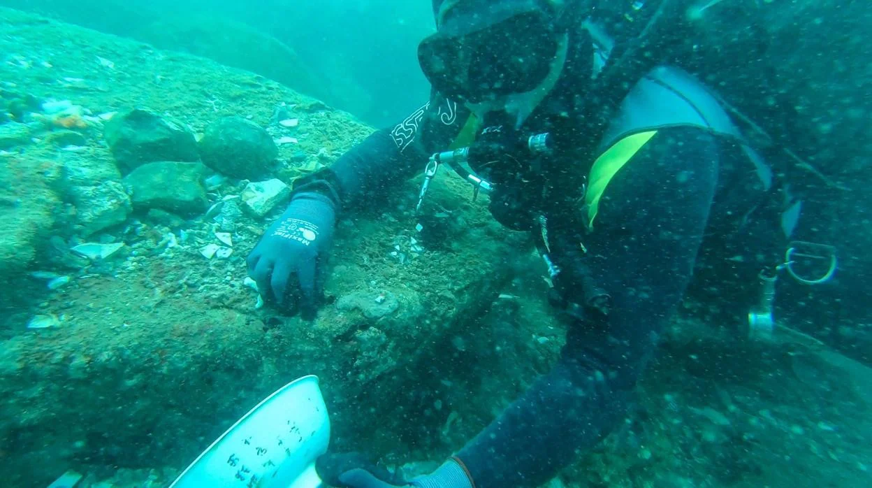 Un buzo muestra una cerámica hallada junto a los restos de uno de los barcos