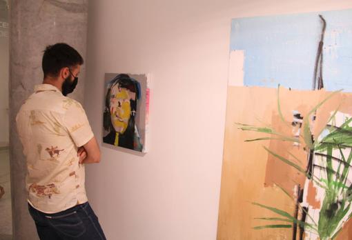 Un hombre contempla las pinturas de Pablo Merchante en DiGallery
