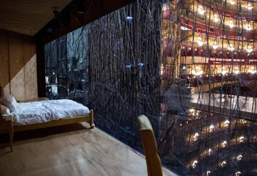 Una cama con arrugas en las sábanas al fondo de la malla metálica