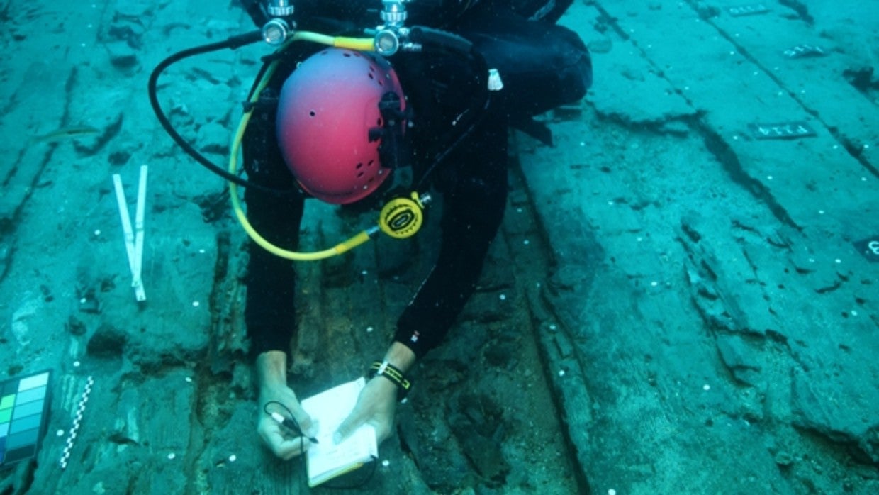 Un arqueólogo subacuático tomando apuntes sobre la arquitectura del pecio