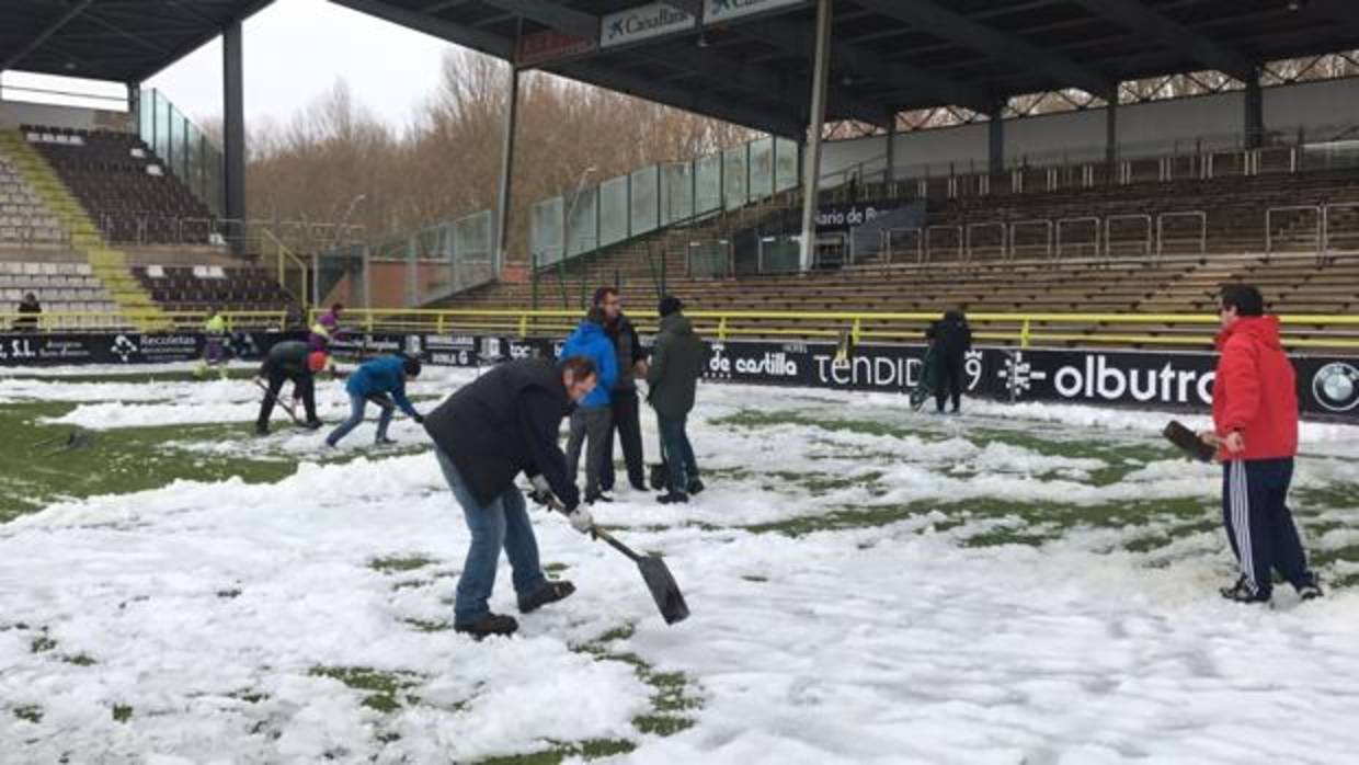 Aficionados del Burgos en El Plantío retirando la nieve este domingo
