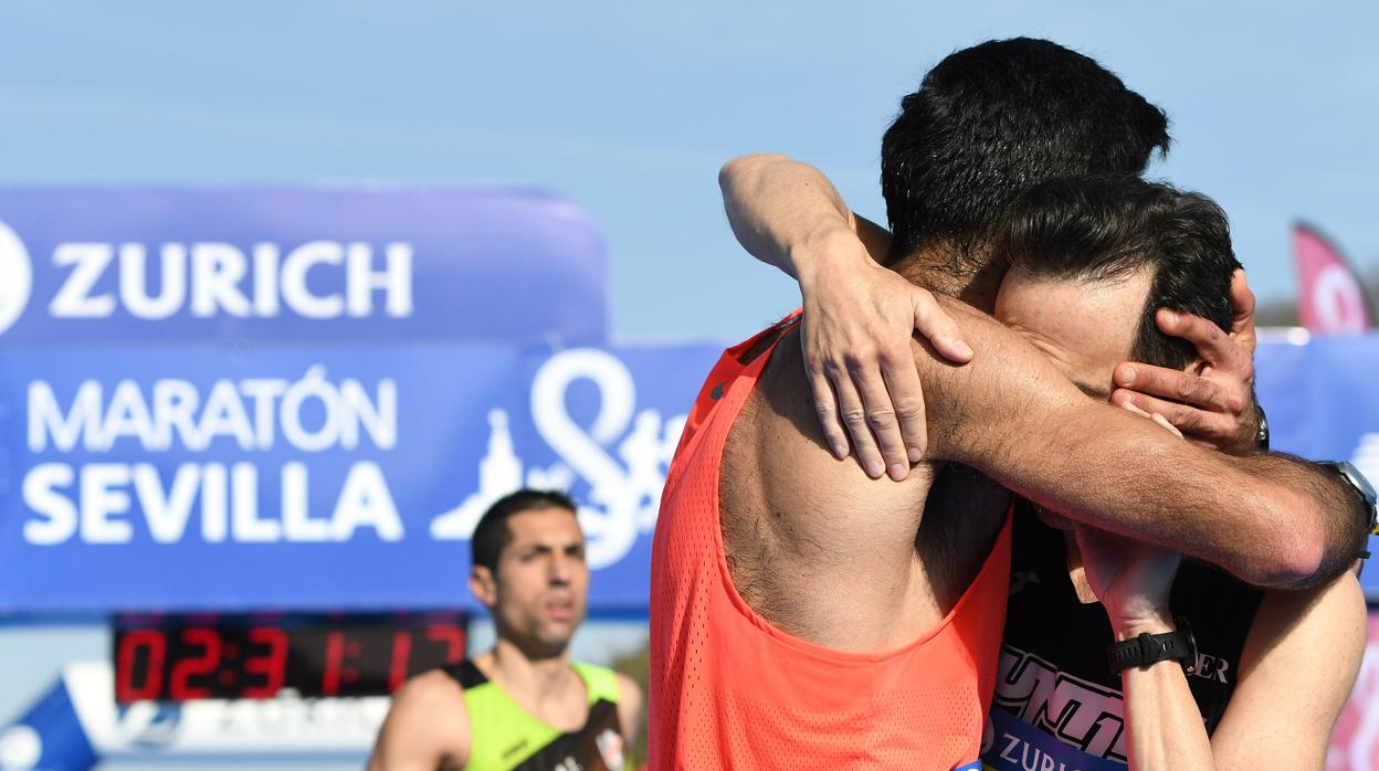 Dos participantes se abrazan tras cruzar la meta del Zurich Maratón Sevilla