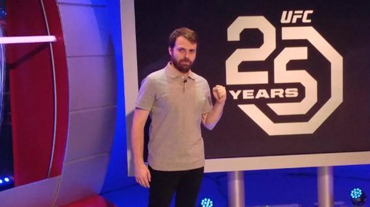 El periodista Albert Fernández posa ante el logo del 25 aniversario de UFC