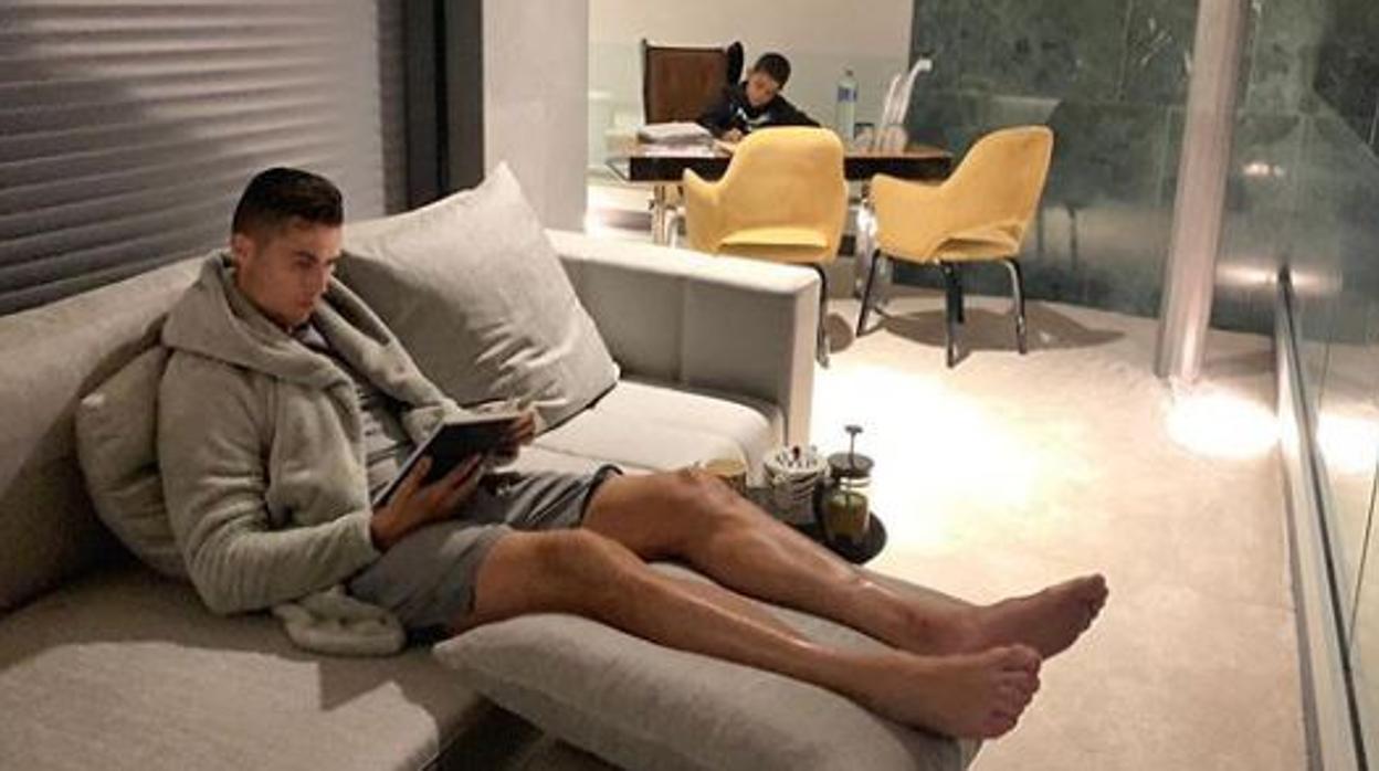 Cristiano Ronaldo lee un libro en su casa mientas, al fondo, su hijo hace sus tareas