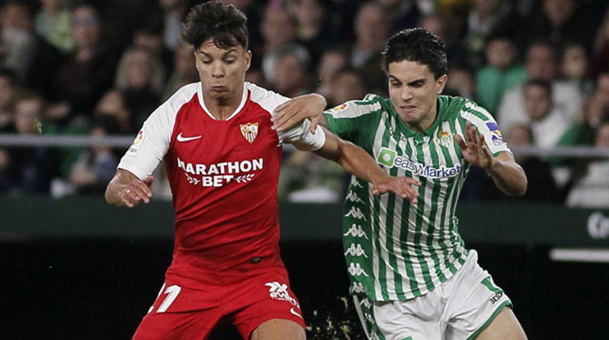 Óliver Torres protege el balón ante Bartra durante el Betis-Sevilla