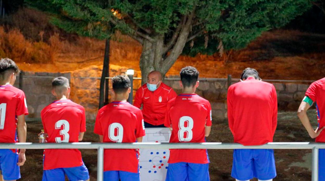 El juvenil B del Granada escucha las lecciones de su entrenador, con mascarilla