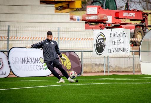 Un jugador de Unionistas calienta en el césped con maquinaria al fondo