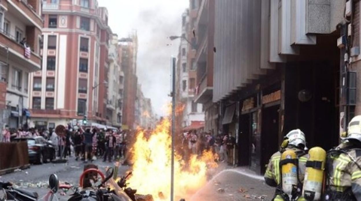 Los bomberos intentan apagar los contenedores incendiados