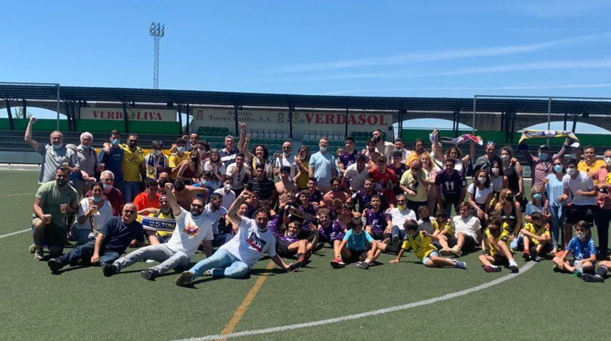 Los jugadores de la UD Tomares, cuerpo técnico, directiva, familiares y aficionados, celebran sobre el estadio municipal de Montilla el ascenso a 3ª RFEF