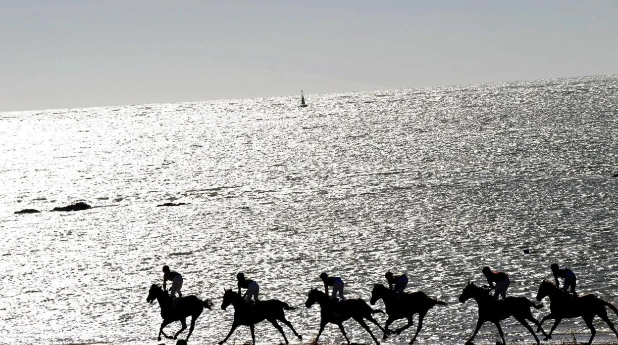 Jinetes en una edición de las carreras de caballos de Sanlúcar por la playa.