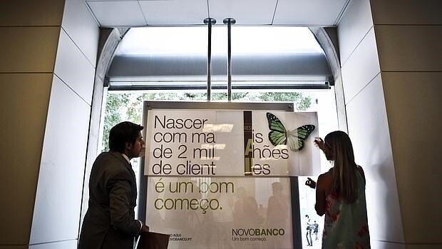 Dos trabajadores cambian el nombre y carteles del Banco Espírito Santo tras la transformación en Novo Banco