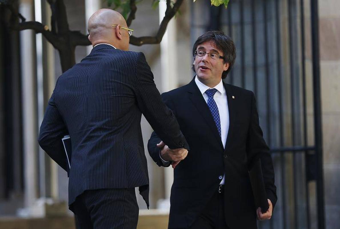 El Presidente de la Generalitat de Cataluña, Carles Puigdemont, se saluda con el Consejero de Exteriores Raül Romeva