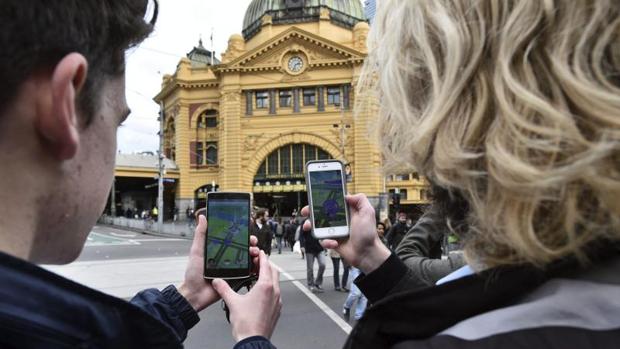 Dos estudiantes prueban el nuevo «Pokémon Go» en su móvil en Melbourne (Australia)
