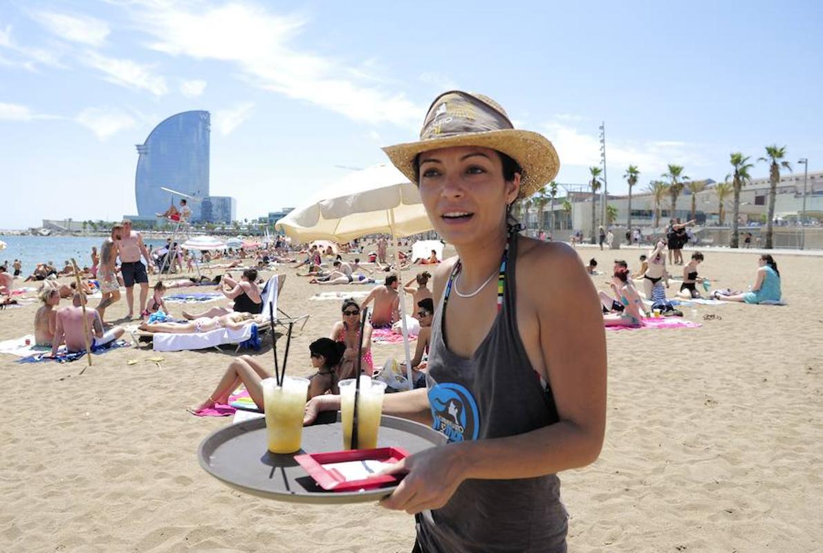 Una camarera sirviendo bebidas en la playa de Barcelona