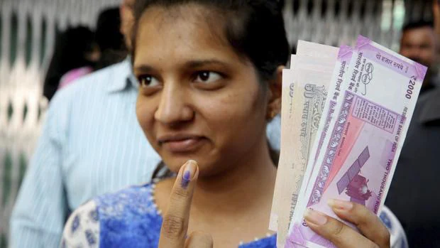 Una mujer muestra su dedo teñido con tinta permanente después de cambiar por otros nuevos los billetes retirados de la circulación la semana pasada, en una sucursal bancaria en Bhopal, en la India