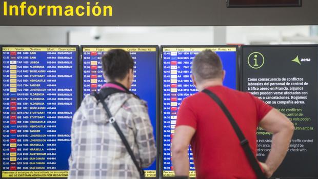 Dos viajeros observan el panel de salidas en el aeropuerto de El Prat (Barcelona)