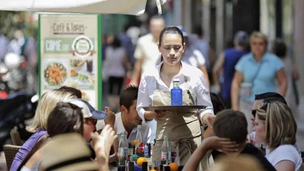 Una camarera atiende a unas mesas de turistas en una terraza de la Plaza del Ayuntamiento de Valencia