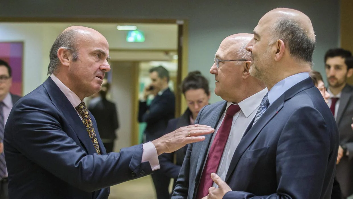 El ministro español de Economía, Luis de Guindos conversa con el ministro de Finanzas de Francia, Michel Sapin y el comisario europeo de Asuntos Económicos y Financieros, Pierre Moscovici, en un Eurogrupo el pasado mes de merzo