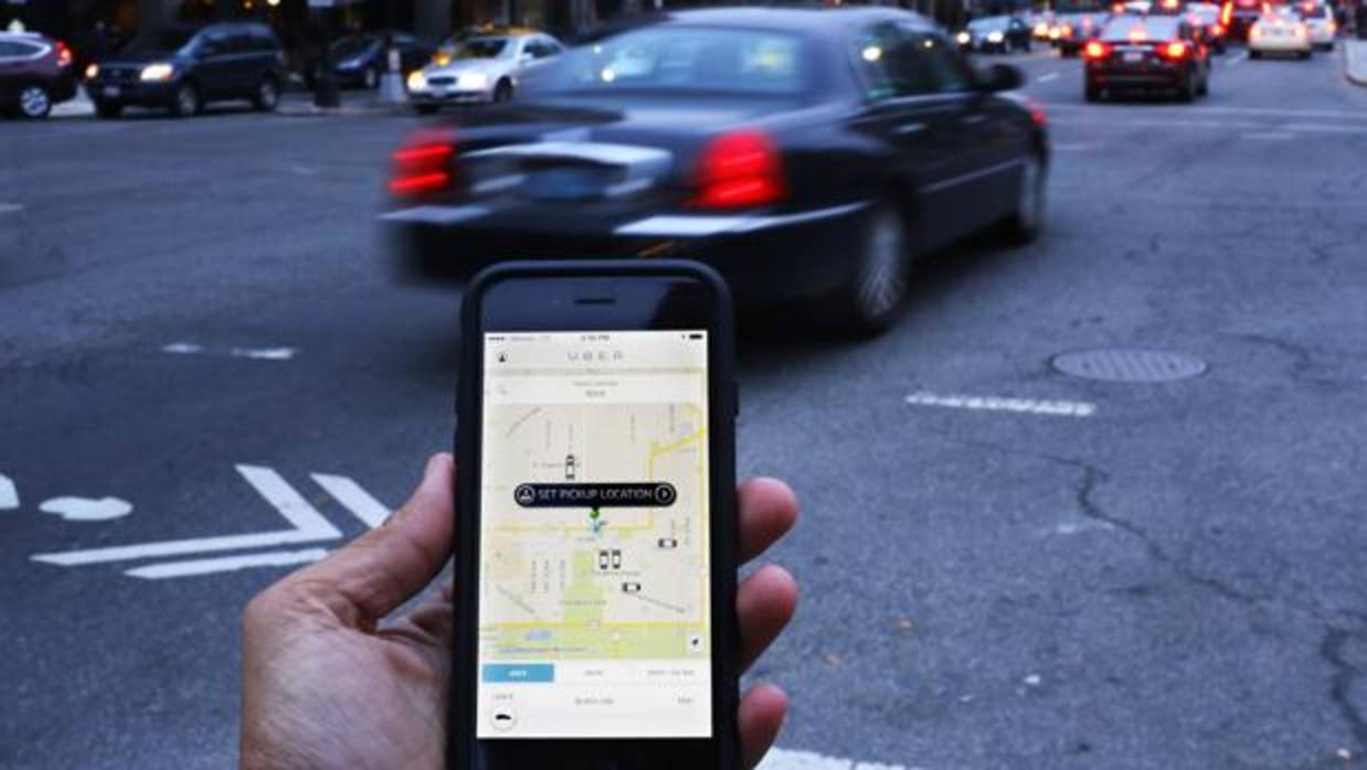 Un usuario de Uber, muestra la aplicación de la compañía en su móvil