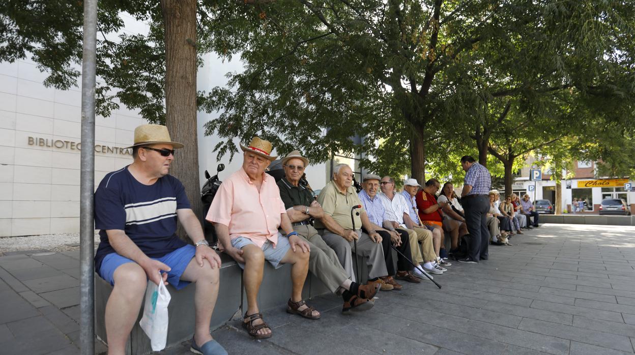 Un grupo de jubilados sentados en un banco en una ciudad española