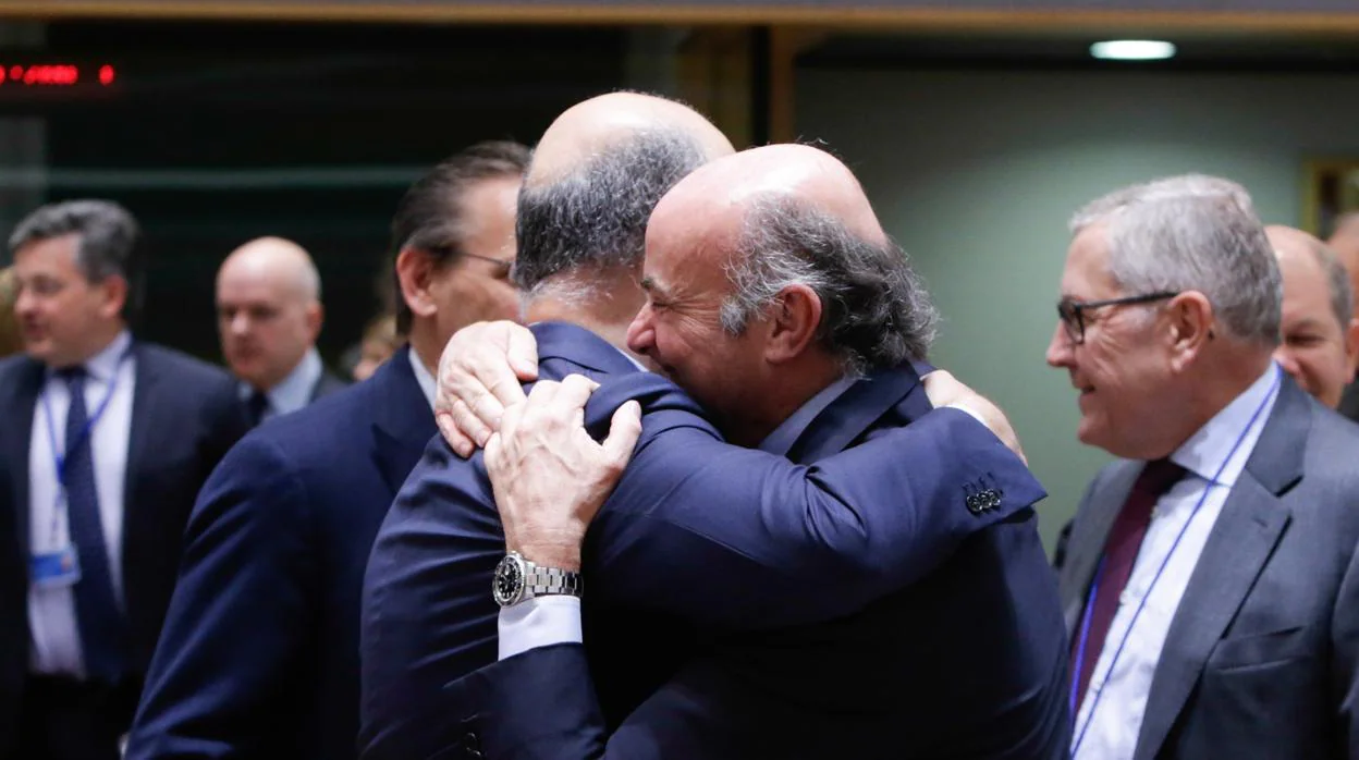El vicepresidente del BCE, Luis de Guindos, se abraza al comisario de Asuntos Económicos, Pierre Moscovici