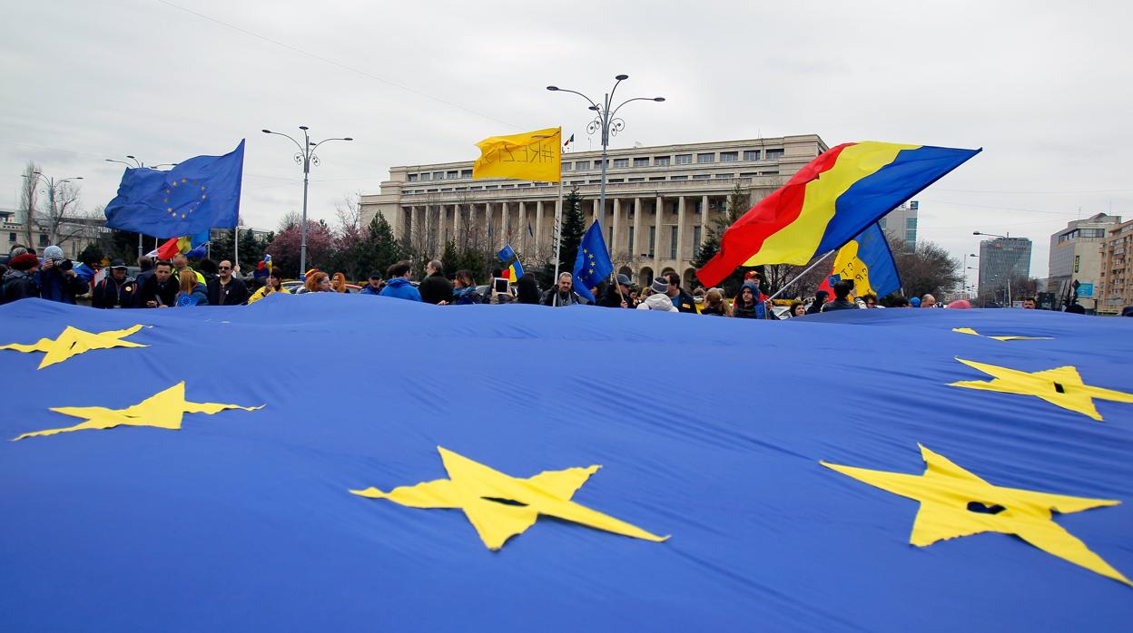 Un grupo de personas junto a una bandera de la UE en Rumanía