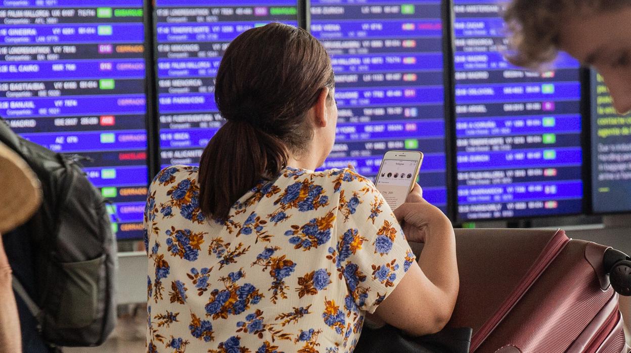 Diferentes viajeros esperan frente al panel de información de los vuelos de Salida del Aeropuerto Josep Tarradellas Barcelona-El Prat, durante la huelga del personal de tierra de Iberia en Barcelona