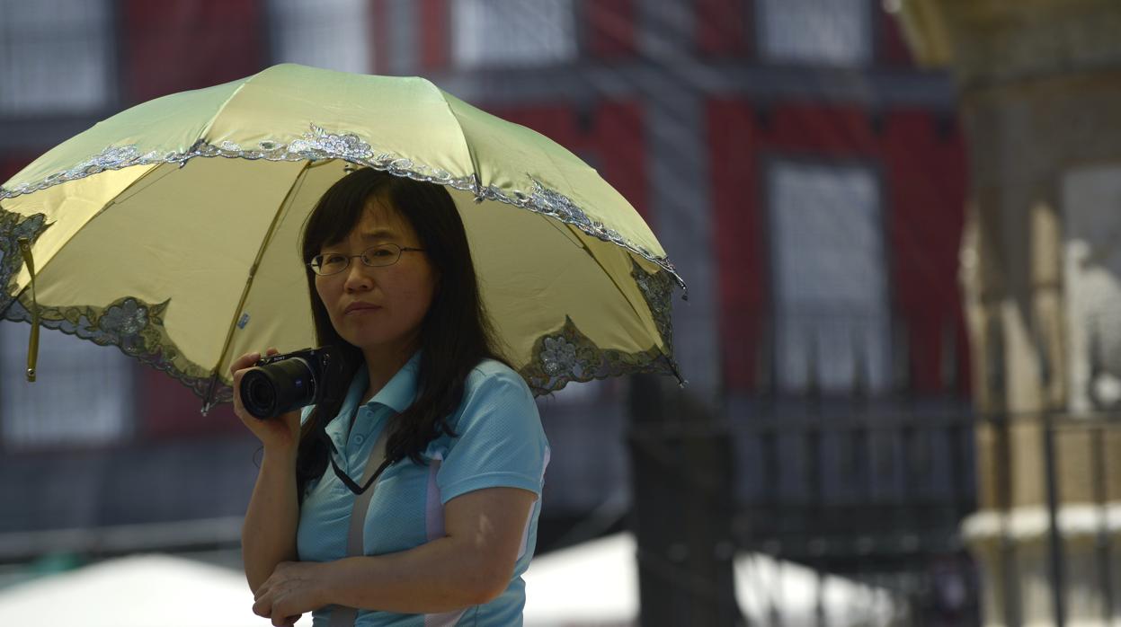 Una turista asiática se protege del sol en un día caluroso de Madrid