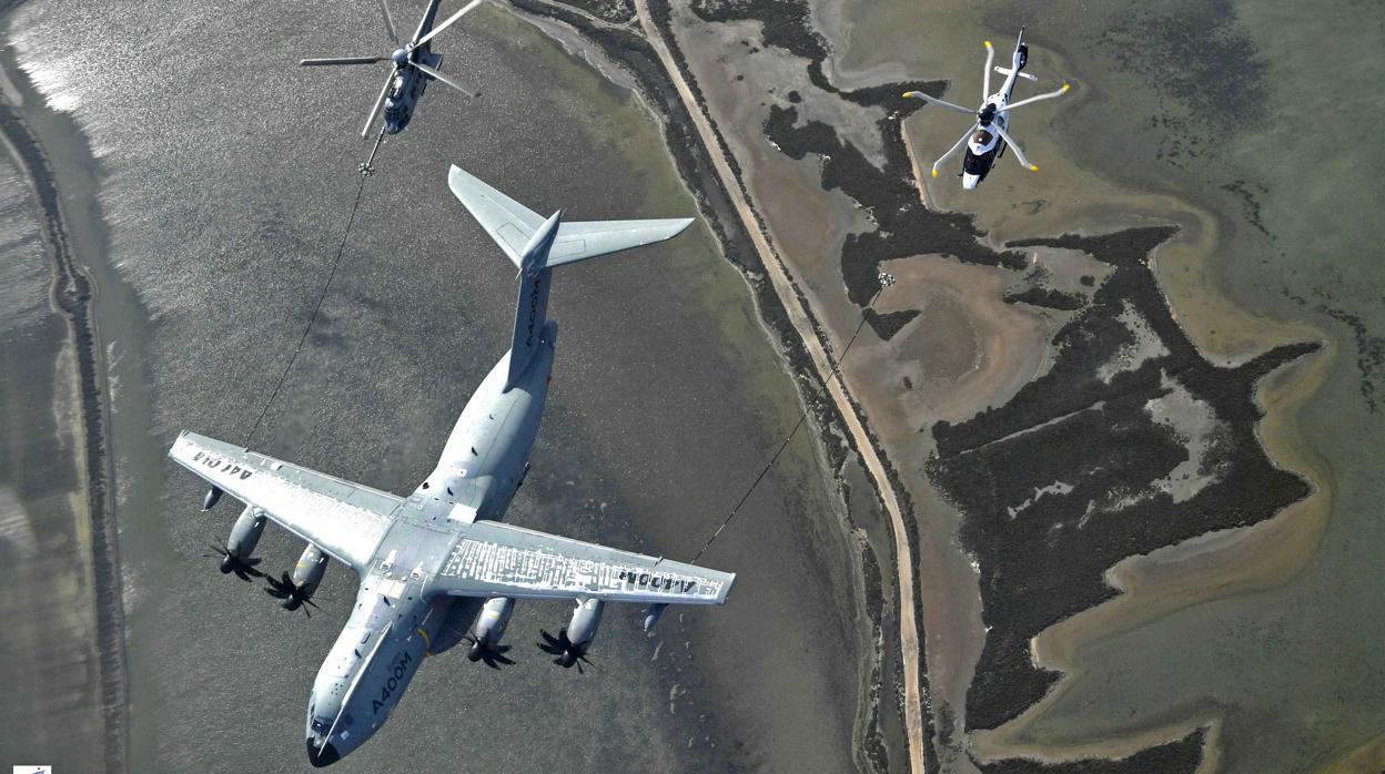 Un avión de transporte militar Airbus A400M contacta para repostaje aeéro con un helicóptero H225M